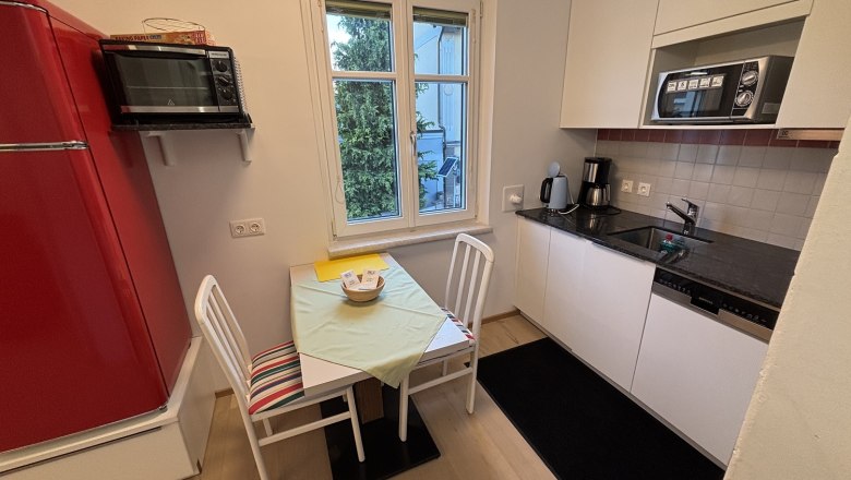 TDR House Morning Sun, © Fam Pauker Small kitchen with red fridge, table, chairs and kitchenette.