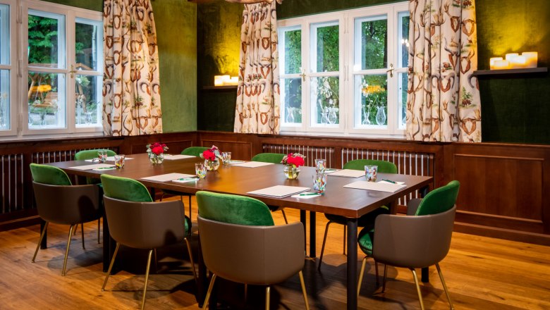 Knappenhof, hunting room, © Hotel Knappenhof, Christian Husar A hunting room with a wooden table, green chairs and antler chandelier.