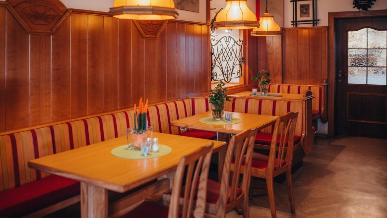 An inn with ballroom, © Niederösterreich Werbung/Daniela Führer Cozy dining room with wooden furniture and red upholstery, decorated with plants and warm light.