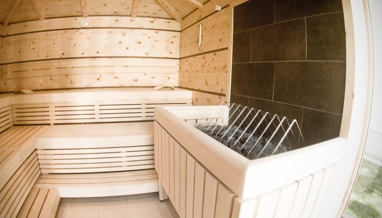 Outdoor sauna, © Römertherme Baden Interior view of a modern sauna with wooden benches and stove.