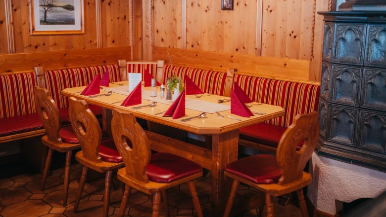Cozy parlor, © Niederösterreich Werbung/Daniela Führer Cozy parlor with wooden furniture, red upholstery and tiled stove.