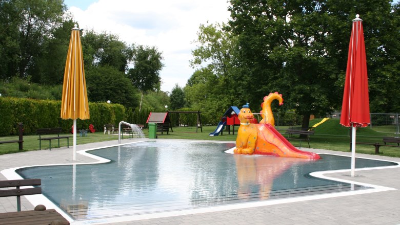 Neunkirchen Recreation Center, © Stadtgemeinde Neunkirchen Children's pool with dragon slide and colorful sunshades at the Neunkirchen recreation center.