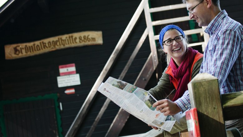 Grüntalkogel hut, © Doris Schwarz König Two people sit in front of the Grüntalkogel hut and look at a map.