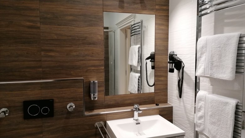 Bathroom in the Aparthotel Goldener Stern, © Inhaber Peter Mayer Modern bathroom with wooden paneling, washbasin, mirror, towel rail and hairdryer.