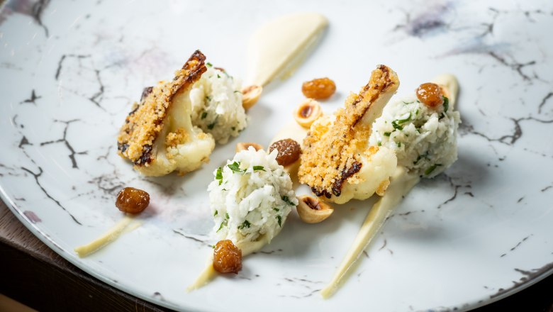 Artfully prepared cauliflower, © Knappenhof Christian Husar Gourmet dish with roasted cauliflower, nuts and raisins on an elegant plate.