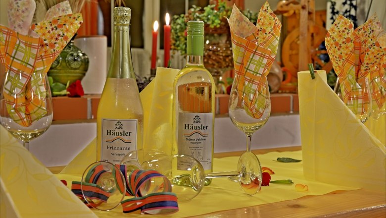 Viticulture Häusler, © zur Verfügung gestellt: Weinbau Häusler Festively laid table with wine bottles and glasses.