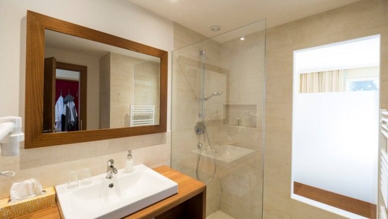 Premium bon-vivant rooms bathroom, © Phtotography Pfeffel Modern bathroom with wooden details, washbasin, mirror and glass shower.