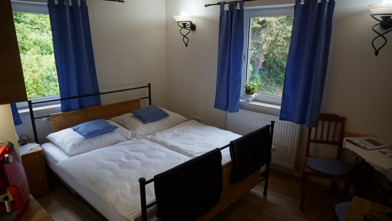 Pension Thayatalblick, © Jörg Riffer Cozy bedroom with double bed, blue curtains and wooden furniture.