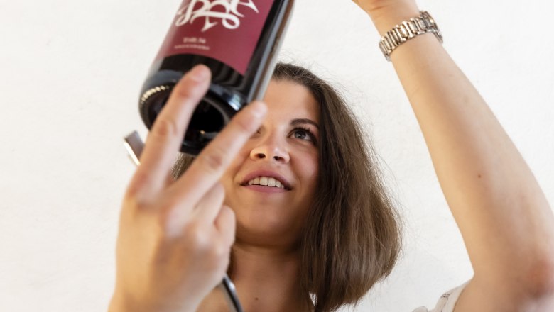 New wine line, © Rainer Friedl Woman inspecting a bottle of wine against the light.
