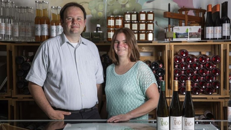 Böhmer Winery, © Monika Loeff Two people stand in front of wine bottles and shelves of products in a winery.