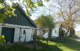 Wine cellar lane Dürnleis, © Gritsch Rural scene with old buildings, trees and a bench in the countryside.