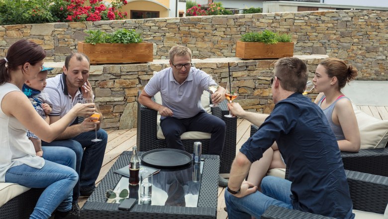 Celebrate on the terrace, © KASTNER NEW MEDIA - kastner.tv Group of people sitting outside on a terrace, toasting with drinks.