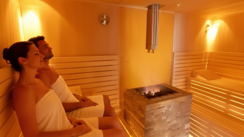 Sauna, © Austria-Best-Hotels Two people relax in a sauna with wooden benches and a stove in the middle.