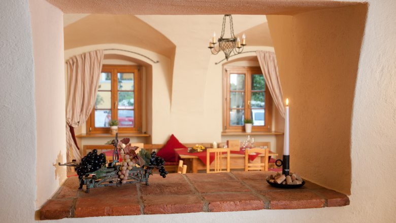 Zirbenstüberl, © Althof Retz View through an opening in the wall into a cozy room with wooden furniture and candlelight.