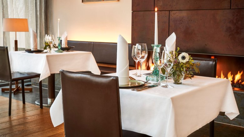 Restaurant Cuve Club, © Steigenberger Hotel and Spa, Gregor Titze Elegant restaurant with laid table, candles and fireplace.