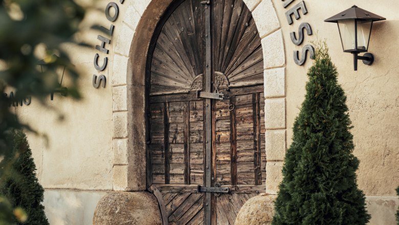 Castle cellar with old press house, two tree presses from 1698, © Niederösterreich Werbung/Julius Hirtzberger Entrance to the castle cellar with wooden door and lettering 'Schlosskeller - Bockfließ'.