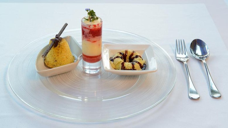 Dessert variation, © Johann Krenn Three desserts on a plate: a cake, a layered dessert in a glass and a small cake ring, with cutlery next to it.