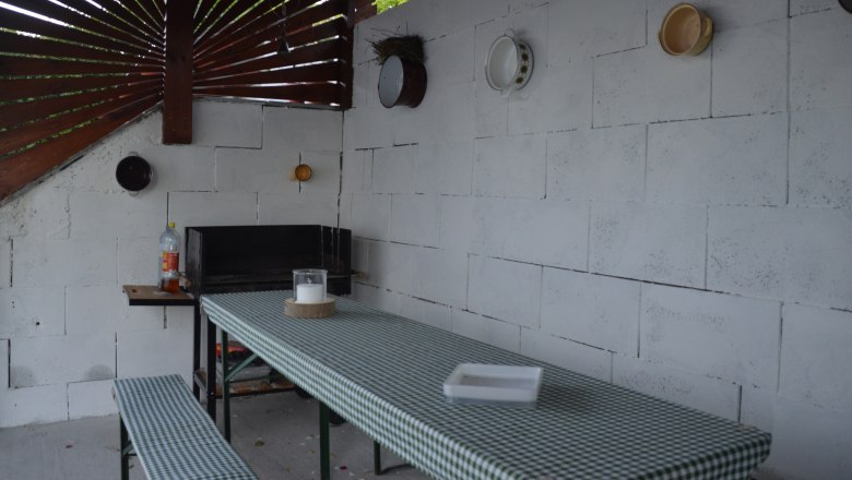 Barbecue area, © Eva Stuhr Covered barbecue area with table and benches, decorated with crockery on the wall.