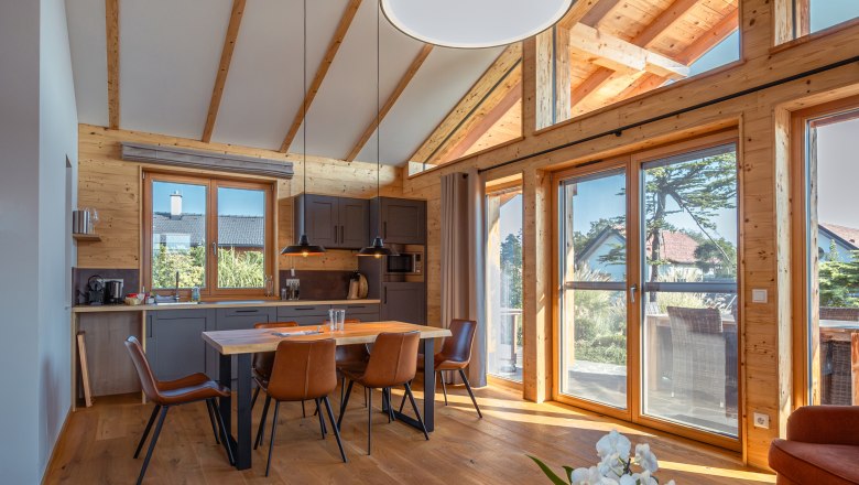 Kittenberger Chalets at the Gartensee, © Niederösterreich Werbung / Maximilian Pawlikowsky Interior view of a modern chalet with wooden beams, dining table and large windows.
