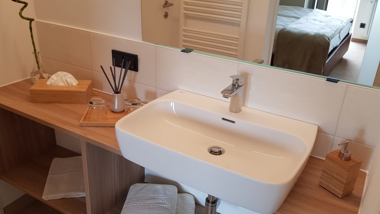 Bathroom, © Alexandra Heiling-Niegl Modern bathroom with washbasin, mirror and wooden shelf.
