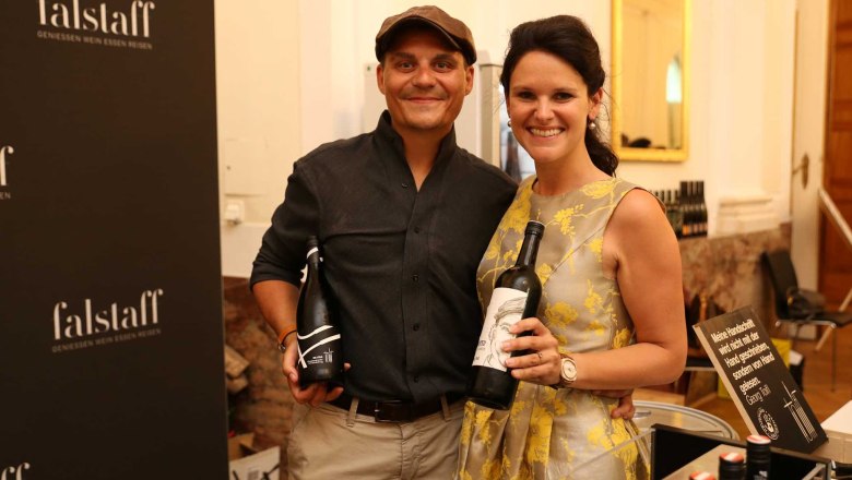 Winery Georg Toifl, © Lukas Kucer Two people holding bottles of wine in front of a Falstaff poster.