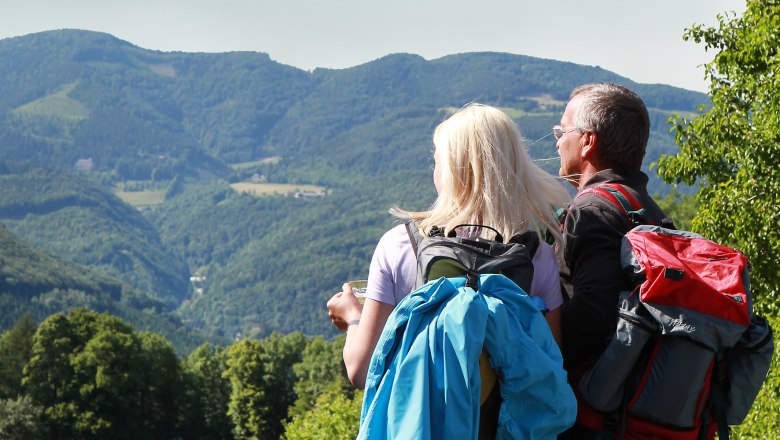 Municipality of Lilienfeld, © weinfranz.at Two hikers with rucksacks look out over a mountainous landscape.