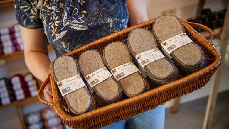 Farm store - Ederers Alpakahof, © Wiener Alpen, Stefan Knittel Person holding a basket of felt shoe insoles in a farm store.