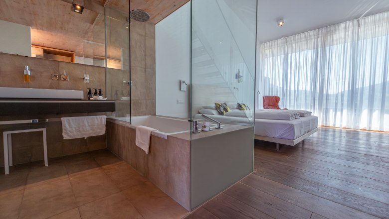 MALAT Winery and Hotel, © Niederösterreich Werbung / Maximilian Pawlikowsky Modern hotel room with glass wall between bathroom and sleeping area.