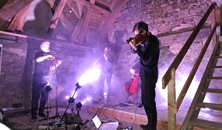 Concerts on the upper floor, © Marktgemeinde Hochneukirchen-Gschaidt Musicians play in a rustic attic with lighting effects.