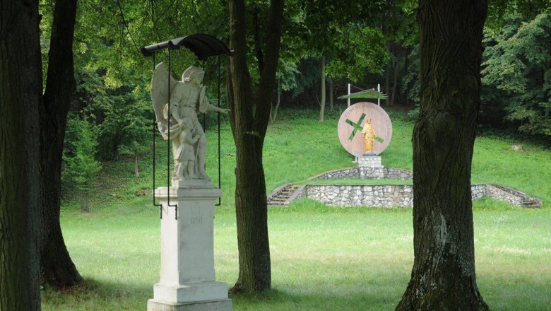 Hohenruppersdorf, © Gemeinde Hohenruppersdorf Statue of an angel with child in the foreground, in the background another statue on a pedestal in a wooded park.