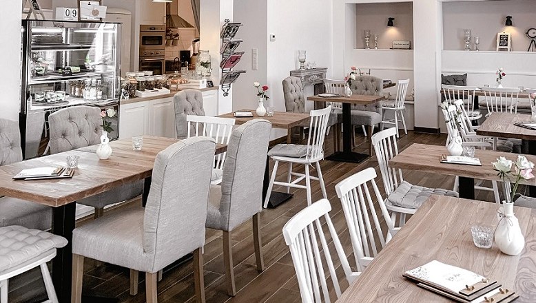 Mille Fleurs Café & More, © Gemeinde Aspang, Mille fleur Interior view of a cozy café with wooden tables and upholstered chairs.