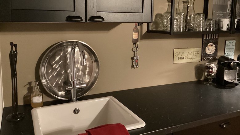 Kitchen unit, © Weitschacher Modern kitchenette with sink, black cupboard, shelves with glasses and coffee machine.