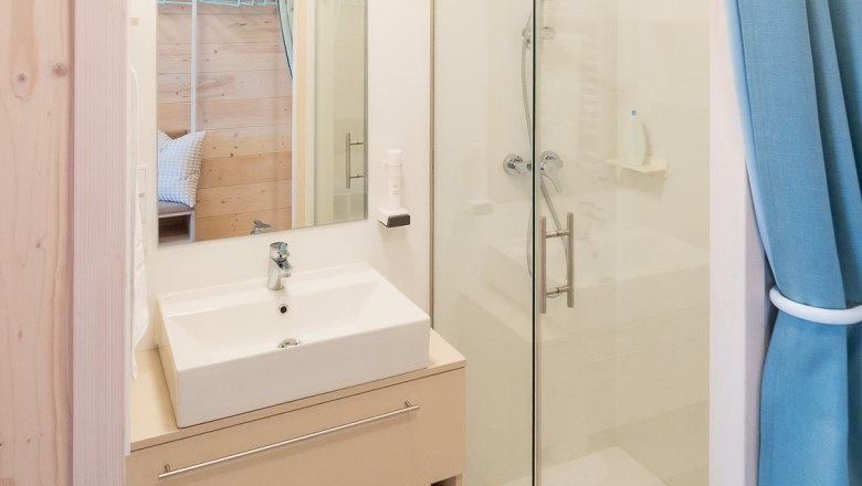 Bathroom, © freilich / IsaBella Fritsche Modern bathroom with washbasin, mirror, shower and blue curtains.