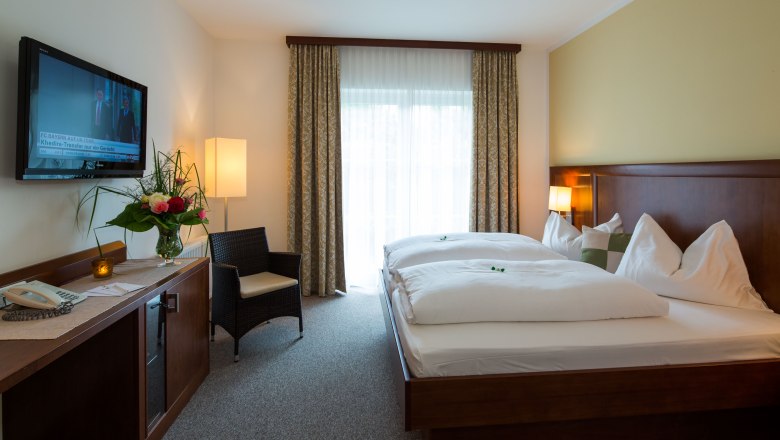 Room, © Tennis Golf Hotel Höllrigl A hotel room with a double bed, TV, armchair and flowers on a table.