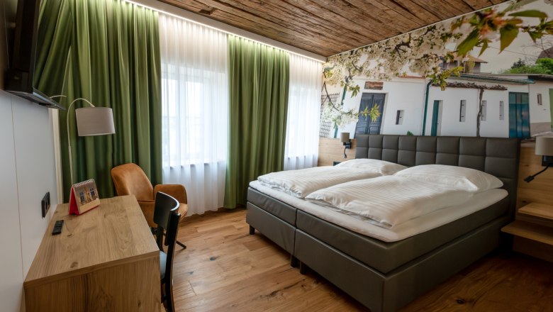Guest room, © Fam. Teufelsbauer Modern guest room with double bed, wooden floor and green curtains.