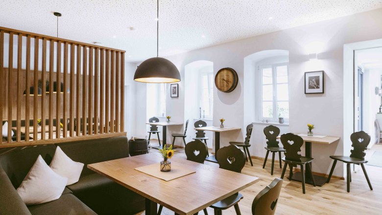 Cozy atmosphere in the light-flooded dining room, © Astrid Bartl Modern dining room with wooden furniture and stylish lighting.