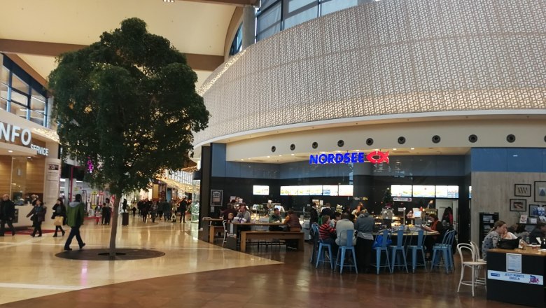 G3 Shopping center, © Roman Zöchlinger Interior view of a shopping center with a North Sea restaurant and a tree in the middle.