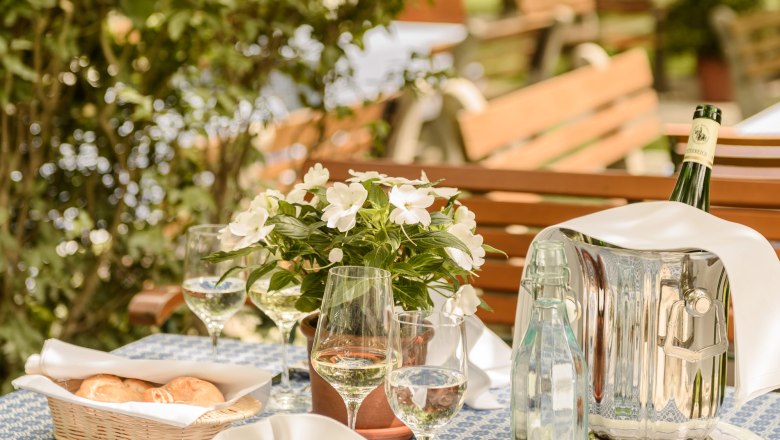 Garden Loibnerhof, © Rita Newman Table set in the garden with flowers, wine and water.