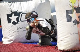Fun and action, © gemeinfrei A paintball player in protective clothing aims a paintball gun behind an inflatable cover.