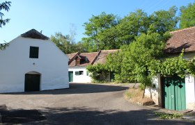Untermarkersdorf wine cellar lane, © Weinviertel Tourismus Traditional wine cellars in a rural setting with trees and blue skies.