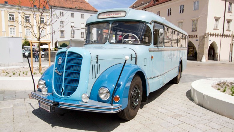 Vintage bus, © Michael Weller A blue vintage bus is parked on a cobbled square in front of historic buildings.