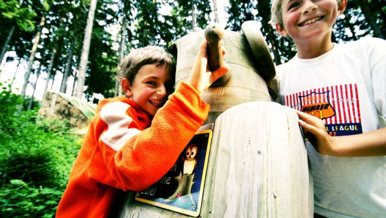 Buchenberg Adventure Park, © weinfranz.at Two smiling children playing on a wooden play set in the forest.