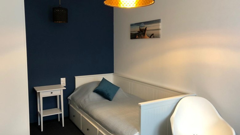 Single room, © Pension zum Spitz A small, modern single room with a bed, a bedside table and a chair.