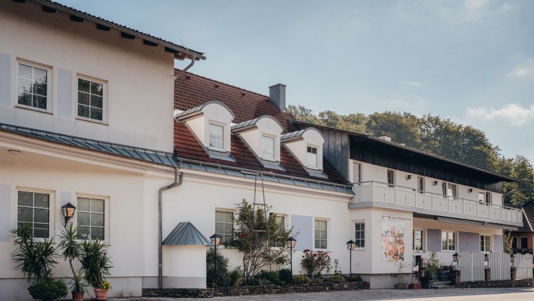 House trout & Sunday buffet are also available here, © Niederösterreich Werbung/Daniela Führer A two-storey building with white walls and red roof tiles, surrounded by plants and lanterns.