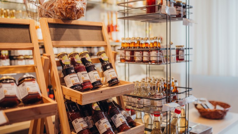 The rose hip store, © Niederösterreich Werbung/Daniela Führer Shelves with jams and syrup bottles in a store.