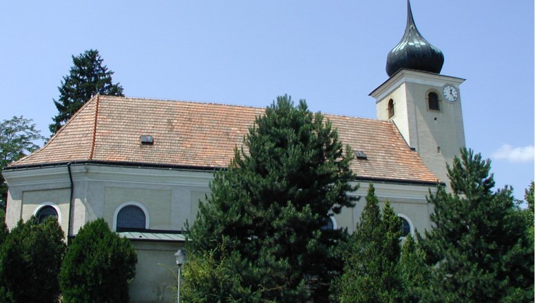 Church in Schleinbach, © Gemeinde Ulrichskirchen-Schleinbach Church in Schleinbach with tower and clock, surrounded by trees.