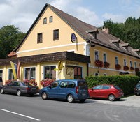 Gasthof Oberer Eggl, © WVAP Perner, Foto Franz Perner A yellow inn with red flowers and parked cars in front of it.
