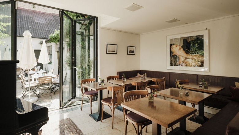 Guest room complemented by vinotheque & wine cellar, © Niederösterreich Werbung/Michael Reidinger Cozy guest room with wooden tables, art on the wall and outdoor terrace.