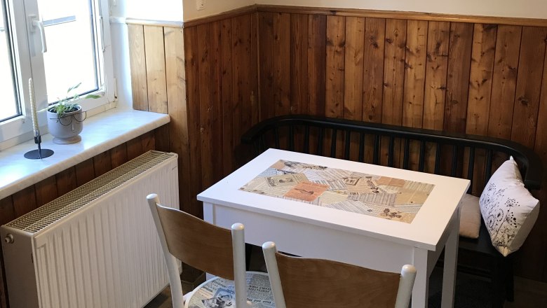 Dining area in the kitchen, © Martina Braun Small dining area with table, chairs and bench in a kitchen with wood paneling.
