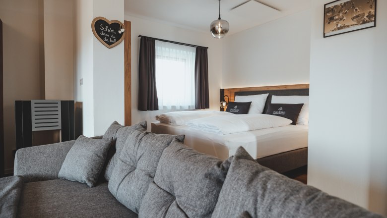 Comfortable and high-quality furnishings, © Chalaalets Modern furnished bedroom with gray sofa and double bed.